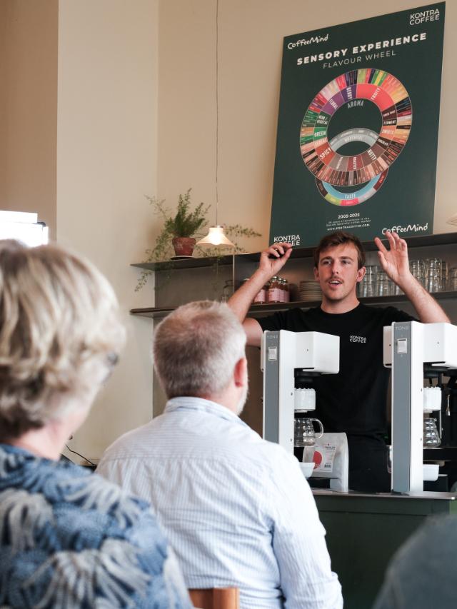 kursusholder underviser i en kaffebar med armene hen over hovedet