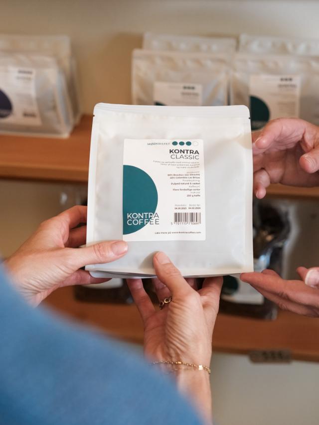 Person holder en pose med kontra coffee mørkristet kaffe i hænderne 