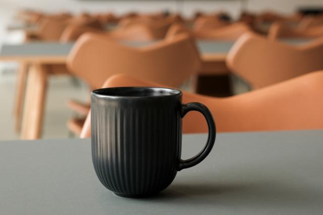 En kaffekop står paa et bord med stole i baggrunden