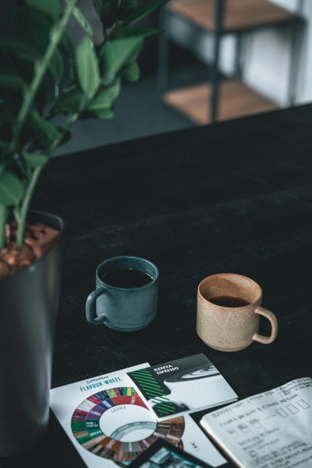 kaffekopper med sort kaffe står paa et skrivebord hvor der ogsaa ligger et smagshjul