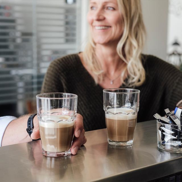 Kvinder smiler og nyder sin firmakaffe