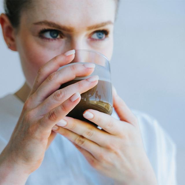 kvinde drikker kaffe fra kaffemaskine til formalet kaffe