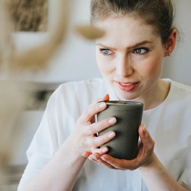 kvinde drikker kaffe malet på kaffekværne