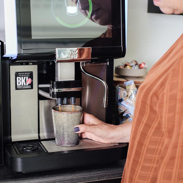 Kvinde trækker kaffe fra fuldautomatisk kaffemaskine fra BKI