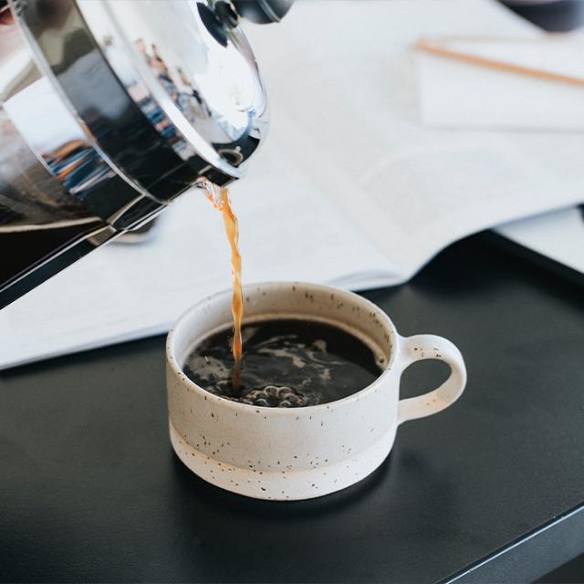 sort kop kaffe hældt fra stempelkande med kværnet kaffe