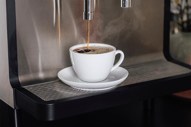 kaffe brygget i hvid kop på kaffemaskine med kaffeløsning til offentlige institutioner
