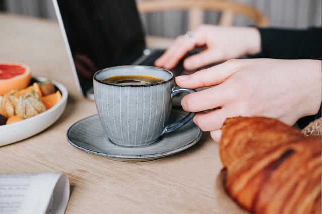 kvinde drikker kaffe fra wittenborg kaffemaskine ved computeren