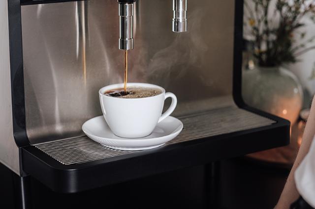hvid kaffekop fyldes af kaffeløsningen til virksomheder og kontorer
