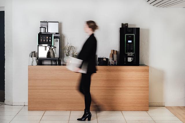 Kvinde hos Horisont går forbi kaffeautomat