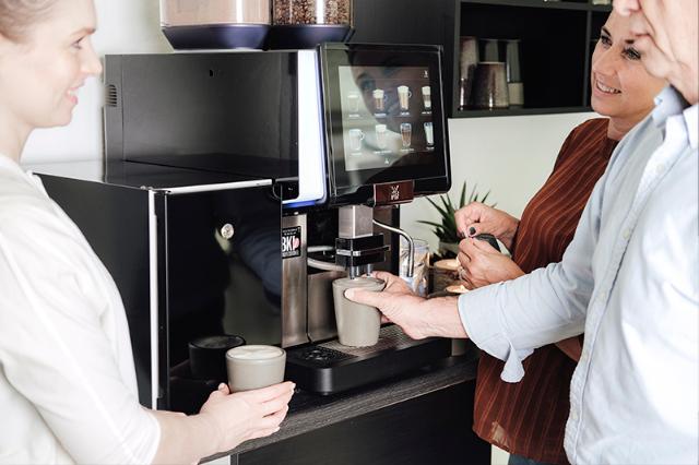 tre kolleger mødes om kaffeløsningen til virksomheder og kontor og drikker kaffe