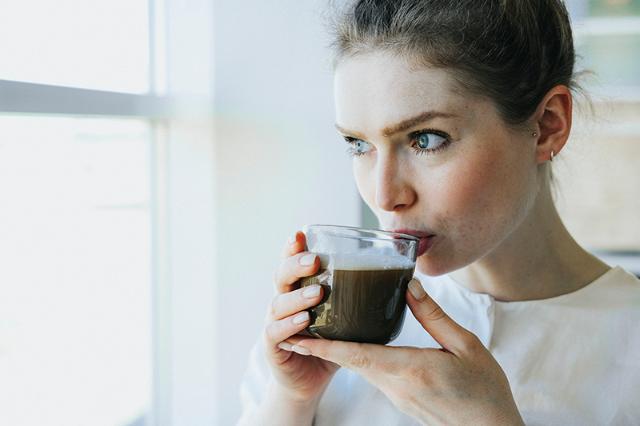 Kvinde drikker kaffe fra kaffemaskine med formalet kaffe