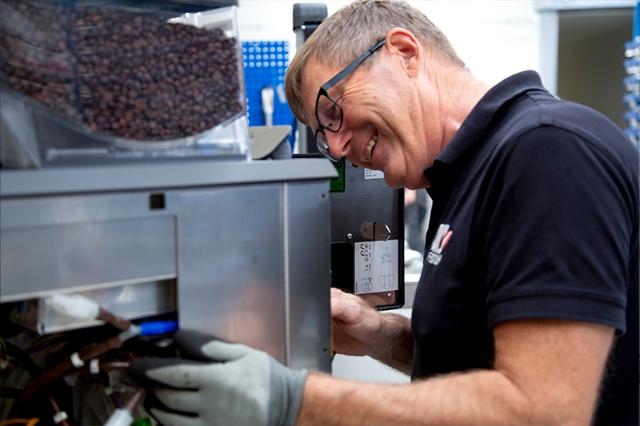 Glad BKI tekniker til service af kaffemaskine som del af kaffeløsning